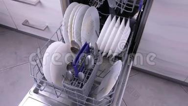 洗碗机篮子，厨房里有脏的白色盘子和餐具。